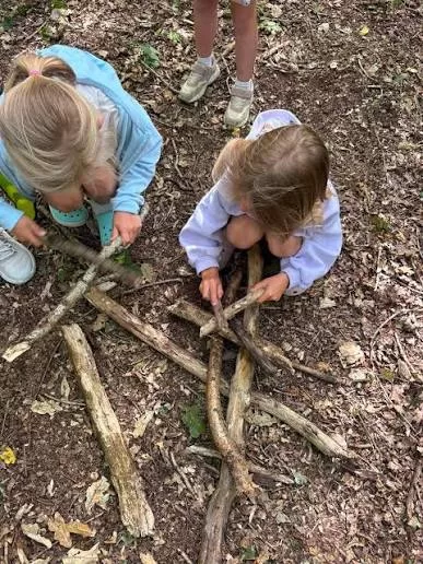 Children exploring sticks and natural materials outdoors at Moss Hall Playcentre